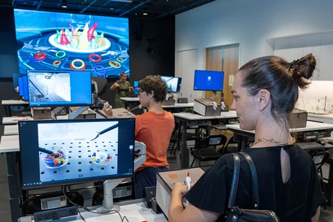 Catherine Nameth, the medical school's director of faculty professional development, tests surgical skills using suturing and laparoscopic box trainers at Rosenfeld Hall opening event. Photo: Reed Hutchinson