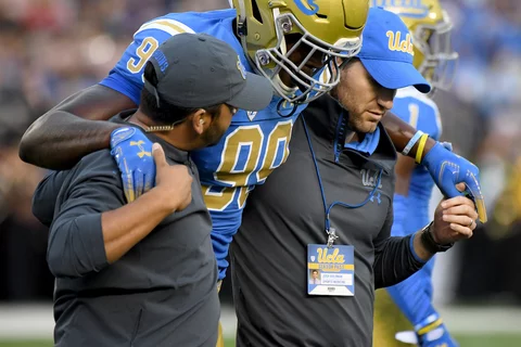 Sports medicine professionals helping an injured UCLA football player off the field 
