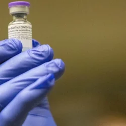 gloved hand holding vaccine