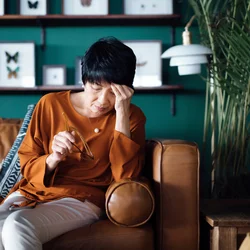 Woman sitting on couch and holding head